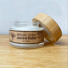 Load image into Gallery viewer, A 50ml jar of Brand Zero Jasmine Butter , shown with its bamboo lid propped open on a light wooden surface against a neutral gray background.

